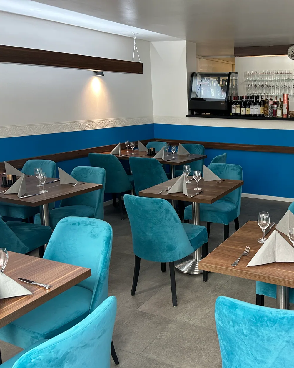 Gedeckter Gastraum von La Pasteria mit blauen Stühlen und Bar
