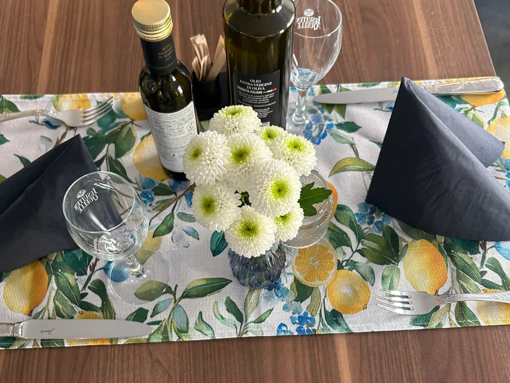Gedeckter Tisch mit Blumen, Gläsern und Olivenöl